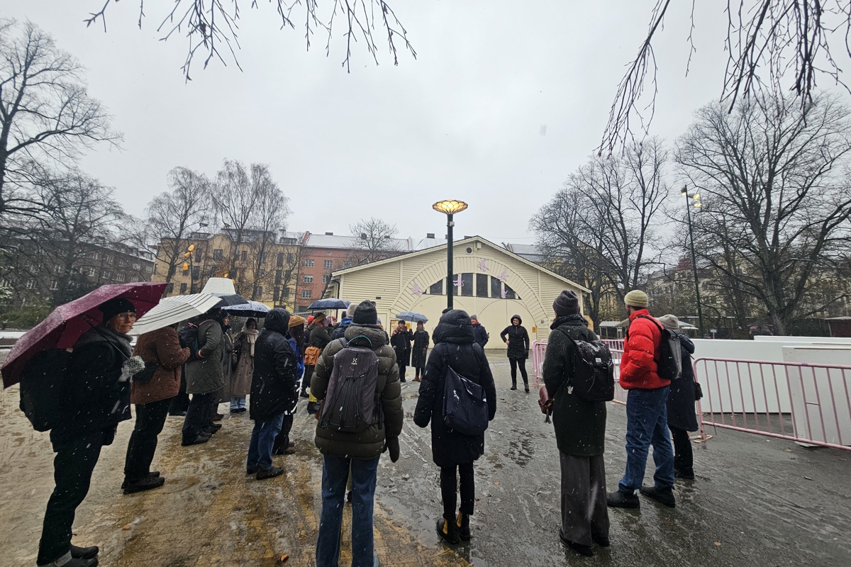 Människor i park framför äldre byggnad. Foto.
