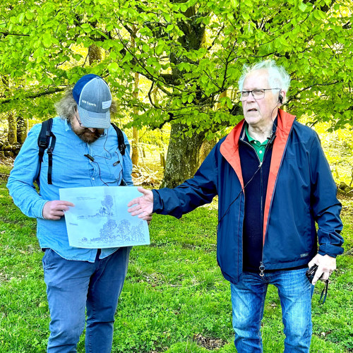 Två personer berättar om träd ute i naturen. Fotografi.