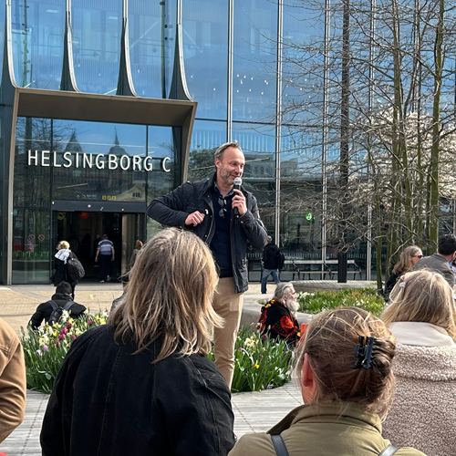 Helsingborgs stadsträdgårdsmästare Martin Hadmyr talar framför grupp av människor vid Helsingborg C. Foto.