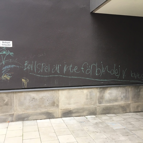 Skylt på vägg: "Bollspel förbjudet", under har barn har skrivit med krita "Bollspel är inte förbjudet, Love soccer". Foto.