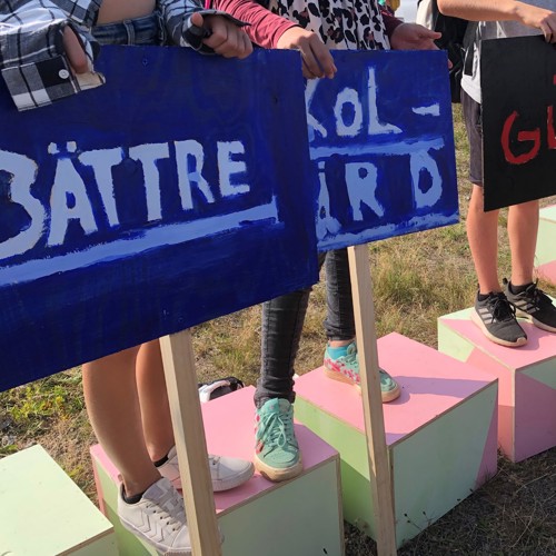 Barn håller skyltar: "Bättre skolgård glada elever". Foto.