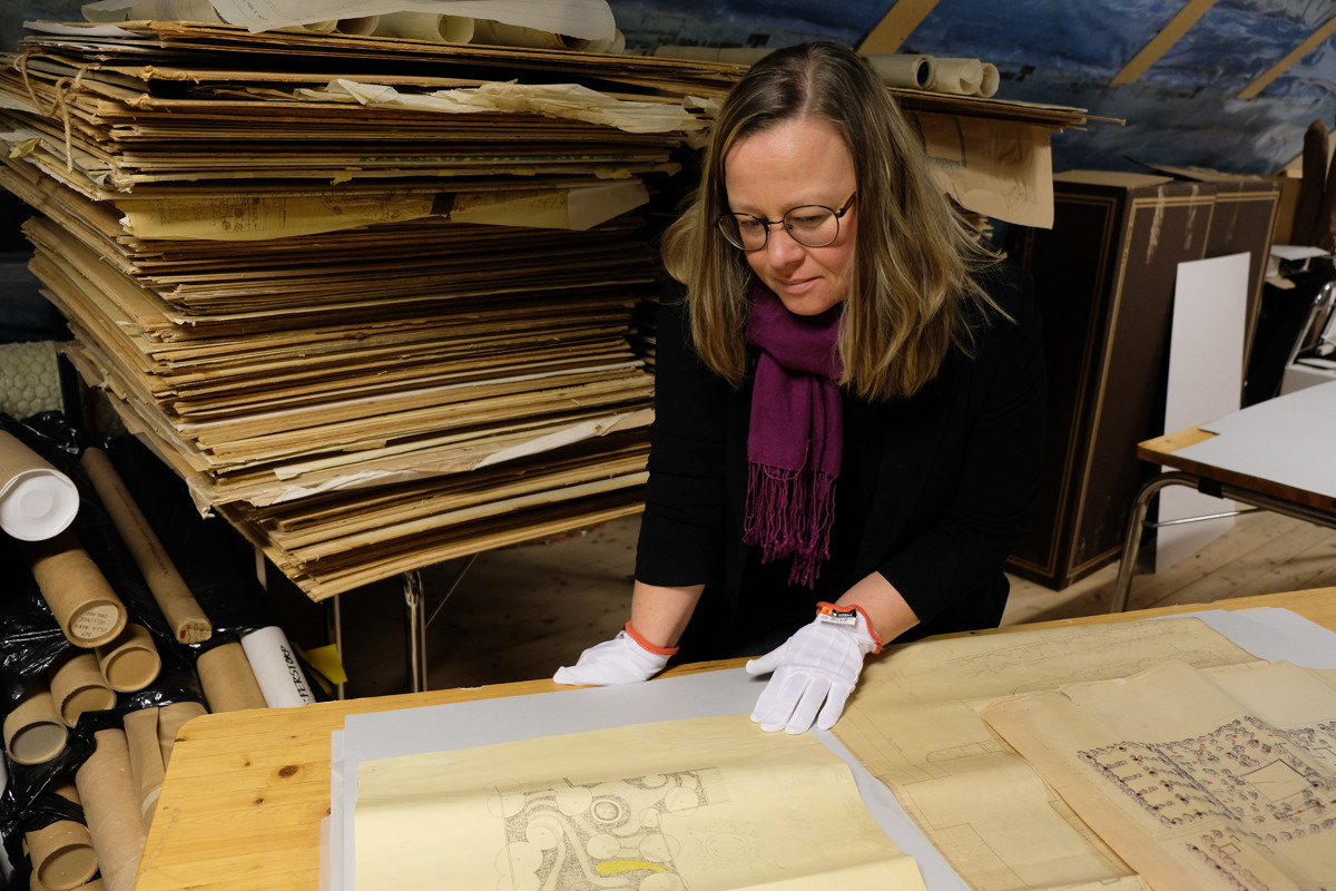 Anna Jakobsson studerar ritningar i arkiv. Foto.