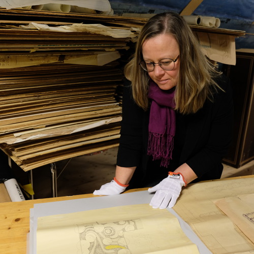 Anna Jakobsson studerar ritningar i arkiv. Foto.