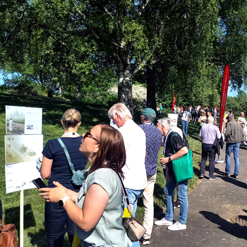 Människor utomhus tittar på affischer med tävlingsbidragen. Foto.