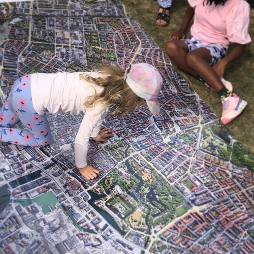 Barn kryper på stor satellitbild av stad. Foto.