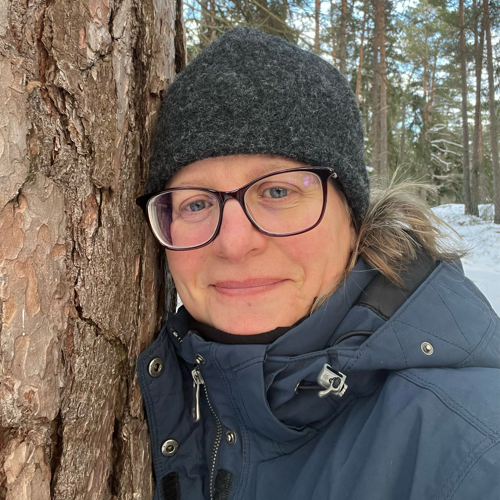 Bild på kvinna vid ett träd. 