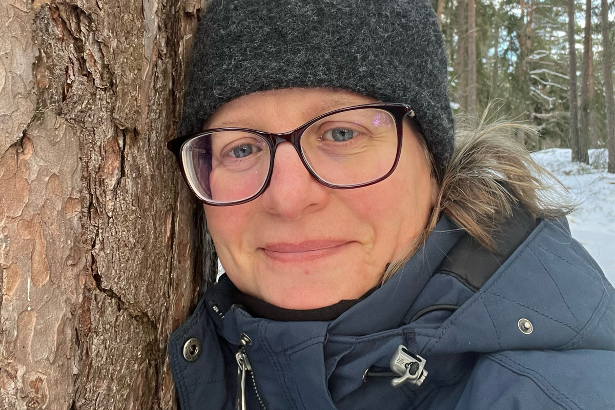 Bild på kvinna vid ett träd. 